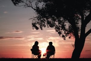 Two people enjoying financial independence and retiring early, while sitting under a tree at sunset.