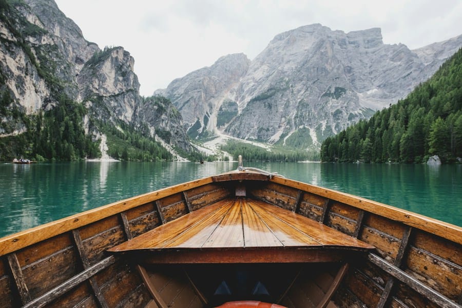 A boat on a serene lake surrounded by majestic mountains, offering the perfect escape for those seeking early retirement and adventurous travel experiences.