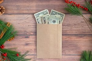 An envelope filled with Christmas money rests on a sturdy wooden table, symbolizing the first steps towards financial freedom through saving for early retirement.