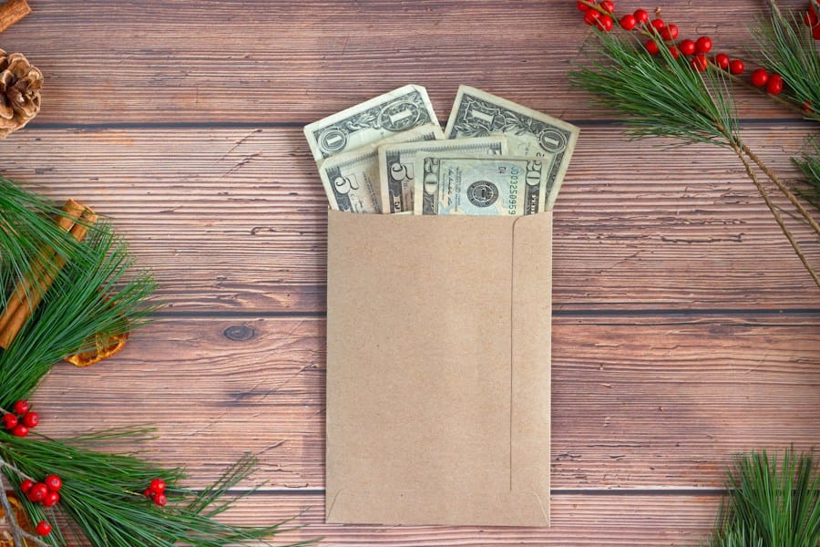 An envelope filled with Christmas money rests on a sturdy wooden table, symbolizing the first steps towards financial freedom through saving for early retirement.