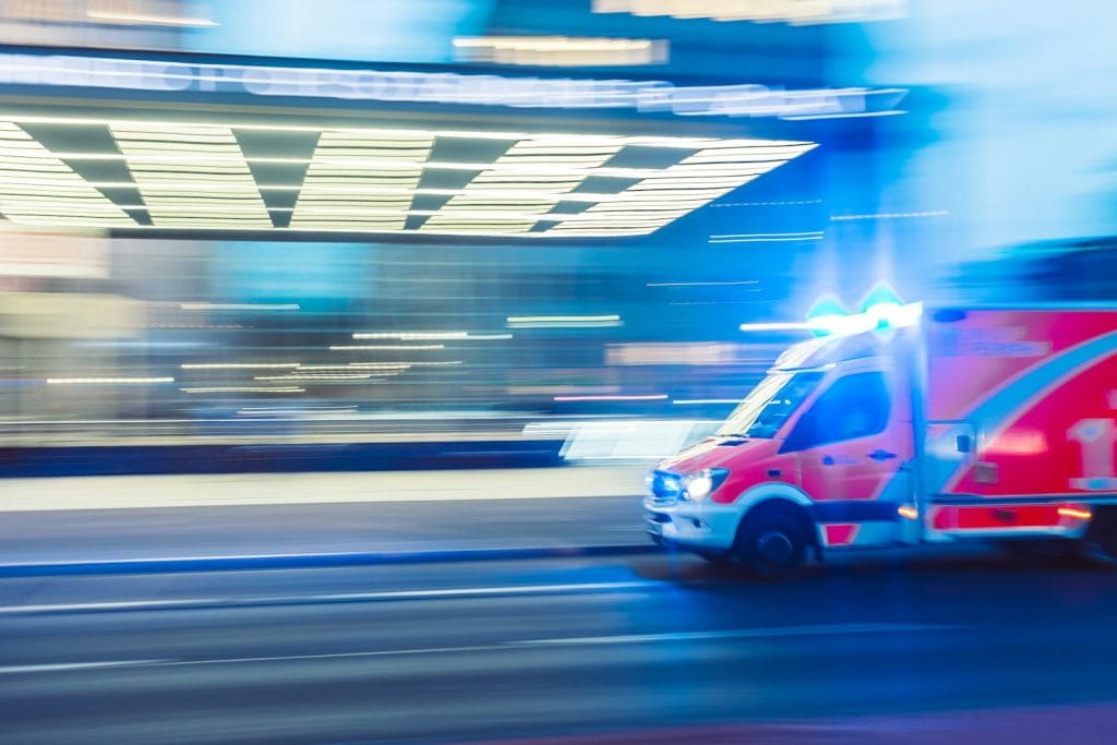 A blurry image of an ambulance driving down the street, providing healthcare on its way to an emergency situation. A reminder of the importance of health insurance in early retirement
