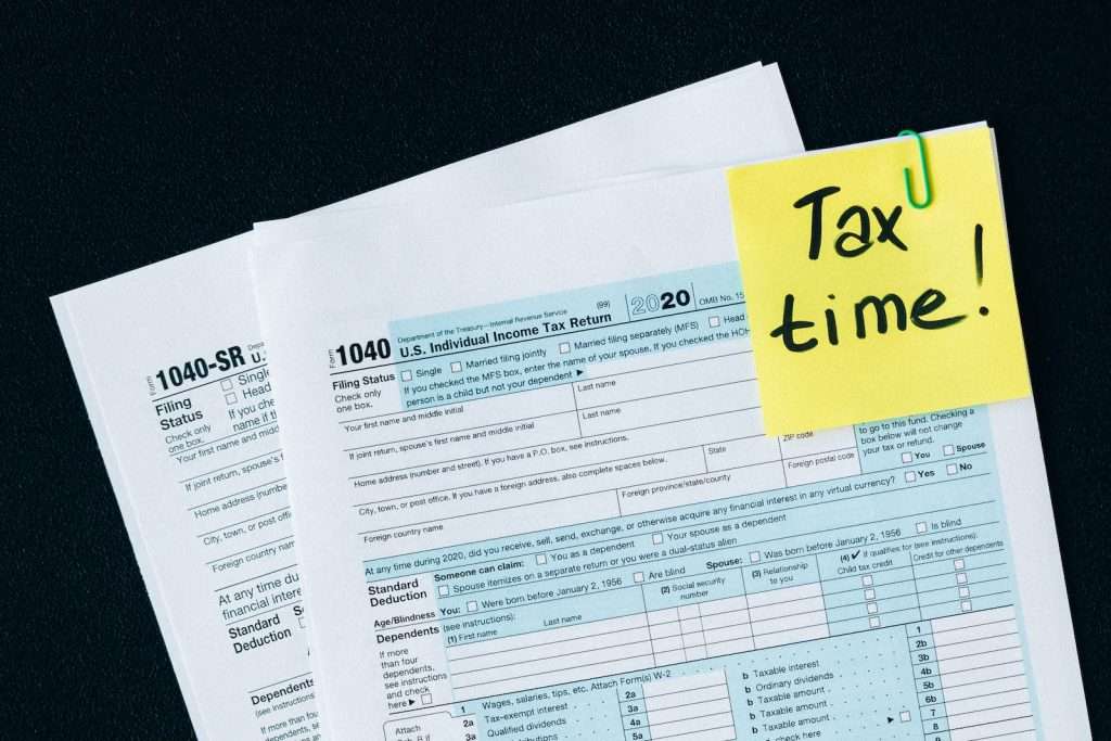 A yellow sticky note with the words "tax time" and "early retirement information" on it.