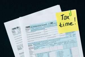 A yellow sticky note with the words "tax time" and "early retirement information" on it.